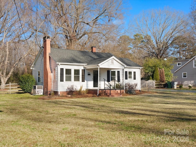 ranch-style home with central air condition unit and a front yard