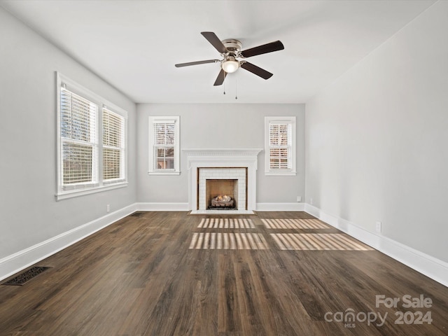 unfurnished living room with dark hardwood / wood-style floors, a brick fireplace, plenty of natural light, and ceiling fan