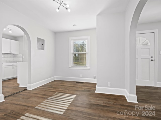 interior space with electric panel, a chandelier, and dark wood-type flooring