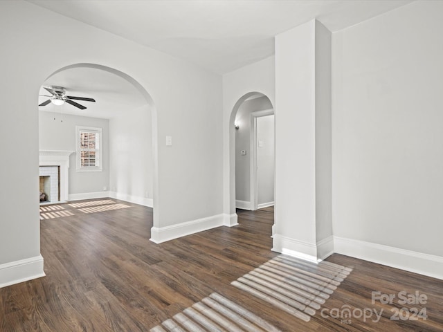 unfurnished room with a fireplace, dark hardwood / wood-style floors, and ceiling fan