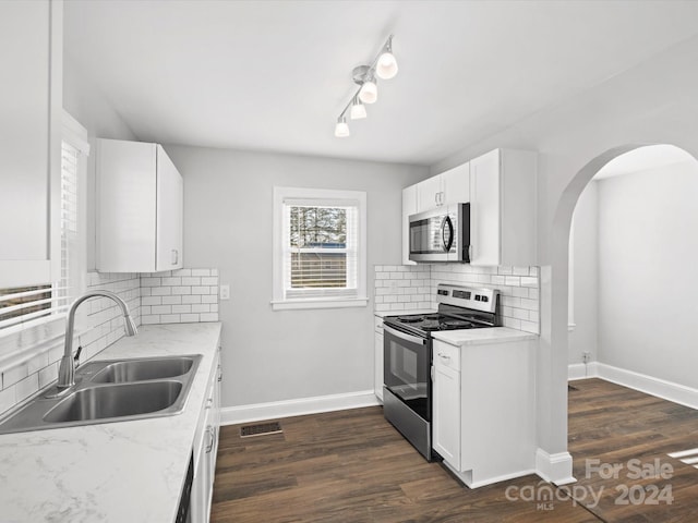 kitchen with sink, stainless steel appliances, light stone counters, backsplash, and white cabinets