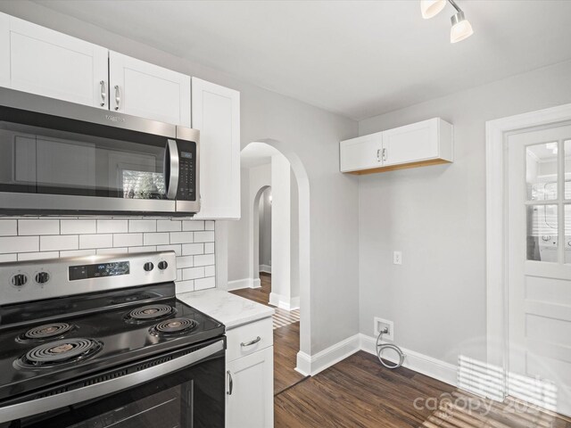 kitchen with dark wood-type flooring, decorative backsplash, light stone countertops, white cabinetry, and stainless steel appliances