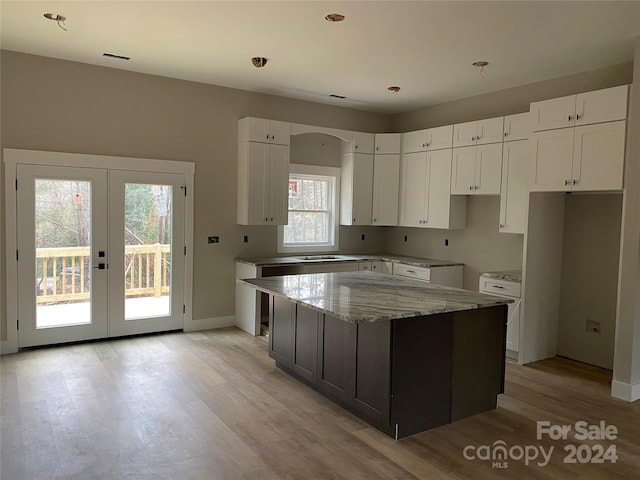 kitchen featuring white cabinetry, a center island, light stone countertops, a healthy amount of sunlight, and french doors