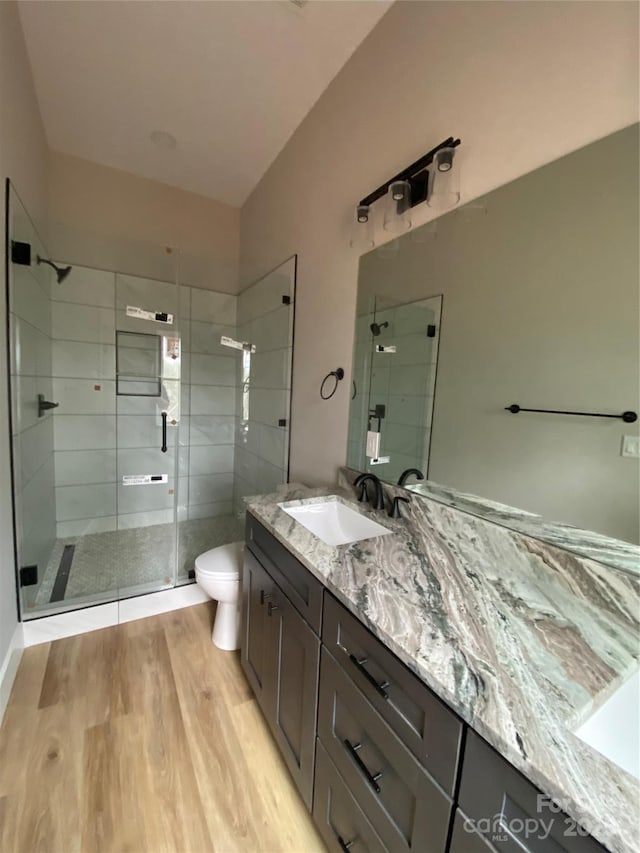 full bath featuring vanity, a shower stall, toilet, and wood finished floors