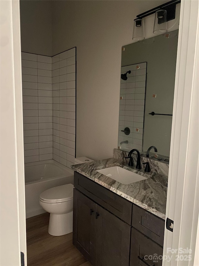 full bath with vanity,  shower combination, toilet, and wood finished floors