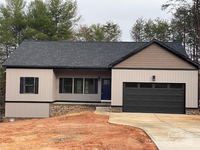 view of front of property with an attached garage, concrete driveway, and a shingled roof