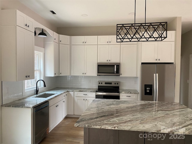 kitchen with light stone counters, a sink, stainless steel appliances, white cabinetry, and tasteful backsplash