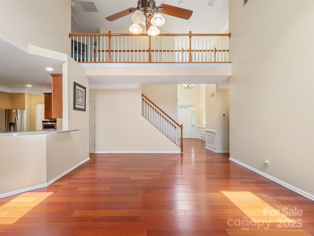 9903 Southampton Commons Dr, Charlotte, NC 28277 - unfurnished living room with a towering ceiling, a ceiling fan, stairway, and hardwood / wood-style flooring