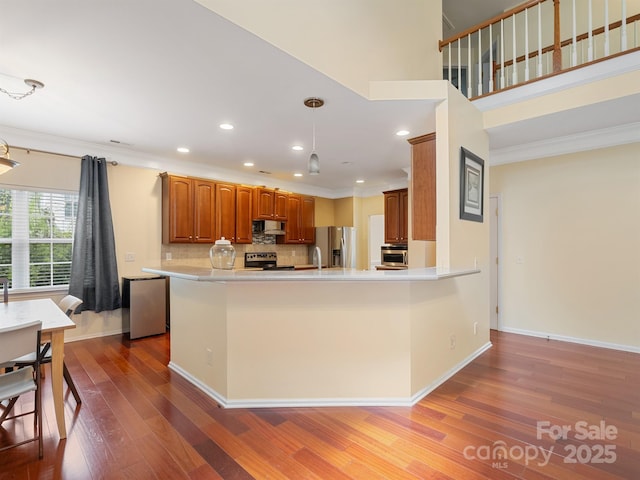 9903 Southampton Commons Dr, Charlotte, NC 28277 - kitchen with appliances with stainless steel finishes, ornamental molding, wood finished floors, brown cabinets, and a peninsula