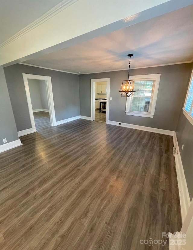 unfurnished living room featuring dark hardwood / wood-style floors, ornamental molding, and a chandelier