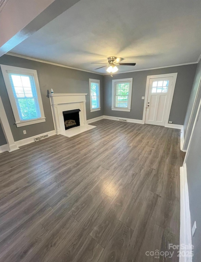 unfurnished living room featuring plenty of natural light, dark hardwood / wood-style floors, and ornamental molding