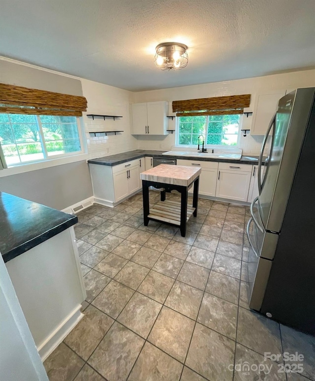 kitchen with decorative backsplash, a textured ceiling, stainless steel appliances, sink, and white cabinets