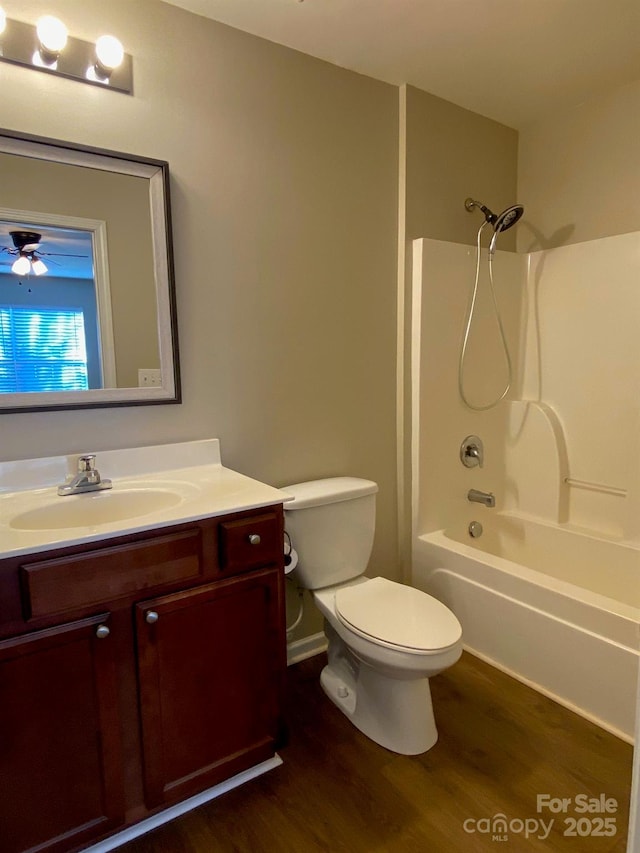 full bathroom with ceiling fan, hardwood / wood-style floors, toilet, shower / washtub combination, and vanity