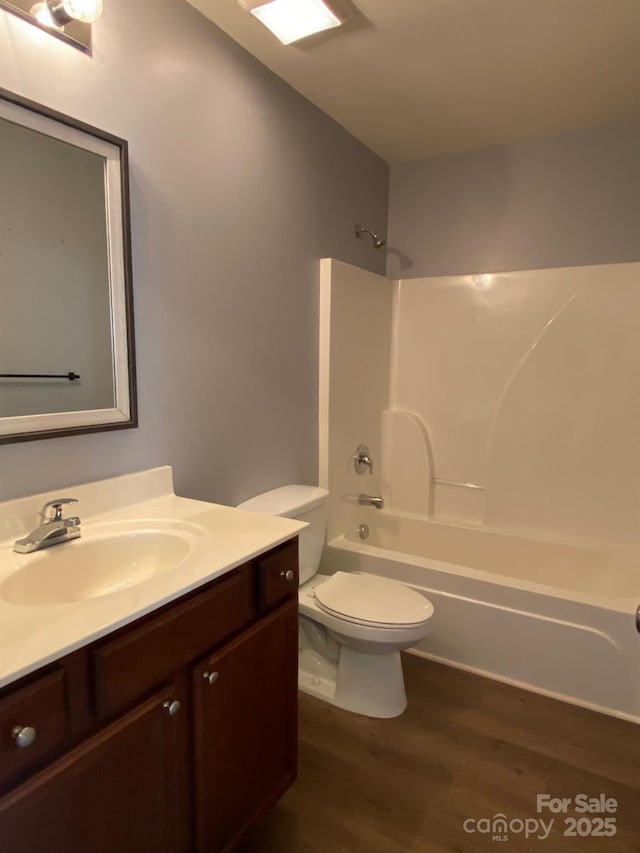 full bathroom featuring vanity, hardwood / wood-style flooring, washtub / shower combination, and toilet