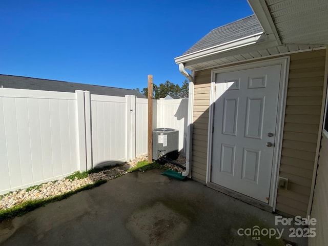 view of exterior entry featuring central AC and a patio area