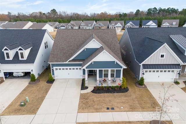 view of front of property with roof with shingles, concrete driveway, covered porch, board and batten siding, and a residential view