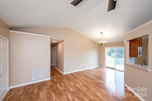 interior space featuring a notable chandelier, light wood-type flooring, a textured ceiling, and vaulted ceiling