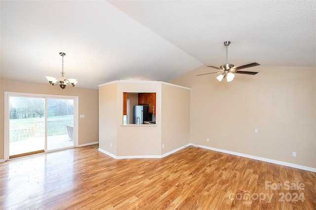 unfurnished living room with a textured ceiling, ceiling fan with notable chandelier, light hardwood / wood-style flooring, and vaulted ceiling