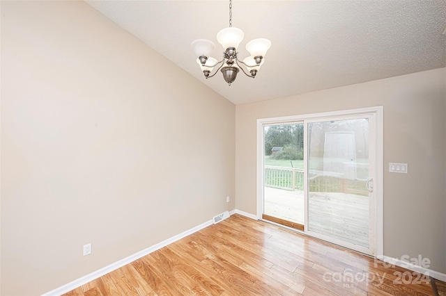 empty room featuring hardwood / wood-style floors, a chandelier, and lofted ceiling