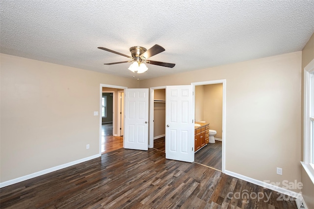 unfurnished bedroom featuring dark hardwood / wood-style flooring, a textured ceiling, ceiling fan, connected bathroom, and a closet