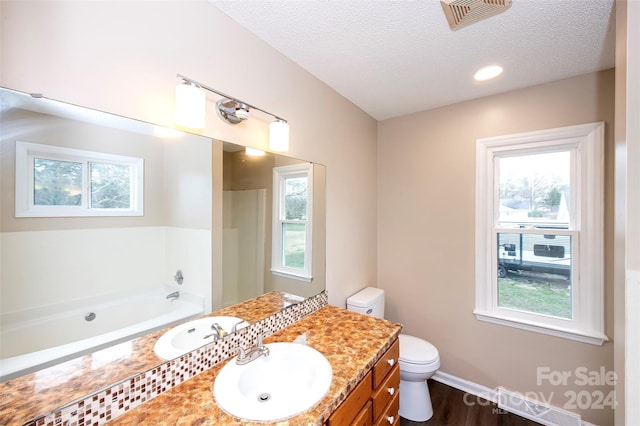 bathroom with a textured ceiling, toilet, a bathtub, vanity, and hardwood / wood-style flooring