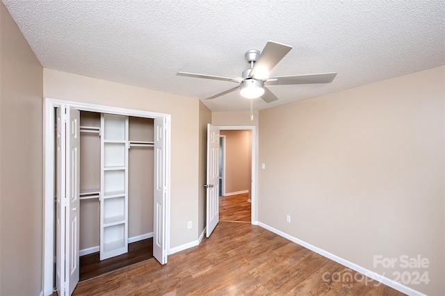 unfurnished bedroom with wood-type flooring, a textured ceiling, a closet, and ceiling fan