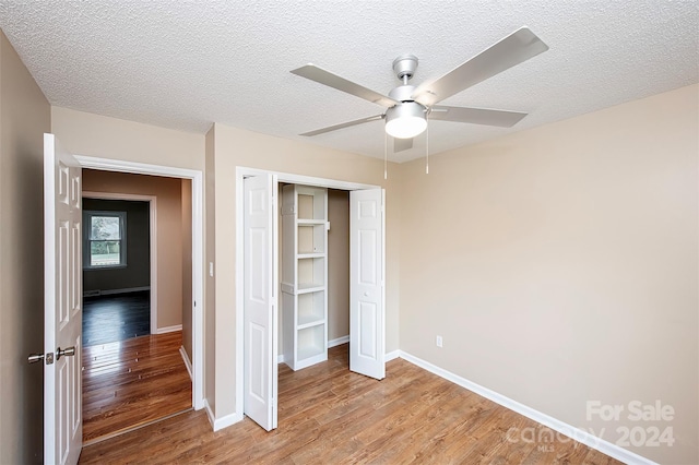 unfurnished bedroom with ceiling fan, a closet, hardwood / wood-style floors, and a textured ceiling