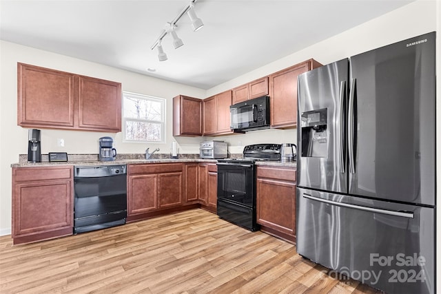 kitchen with sink, light stone counters, light hardwood / wood-style flooring, and black appliances