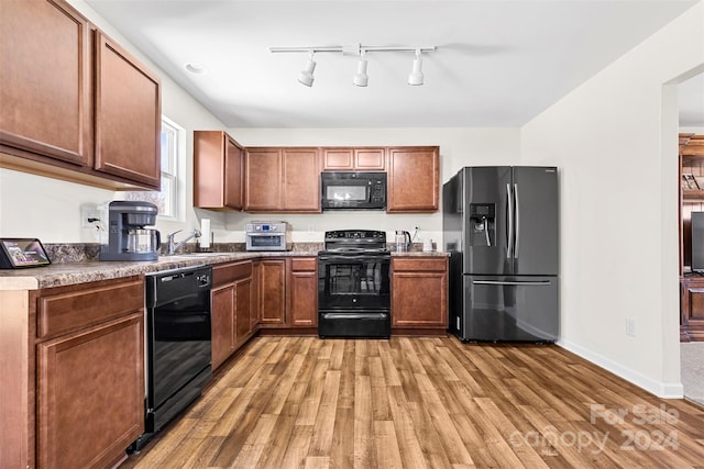 kitchen with sink, light hardwood / wood-style flooring, and black appliances