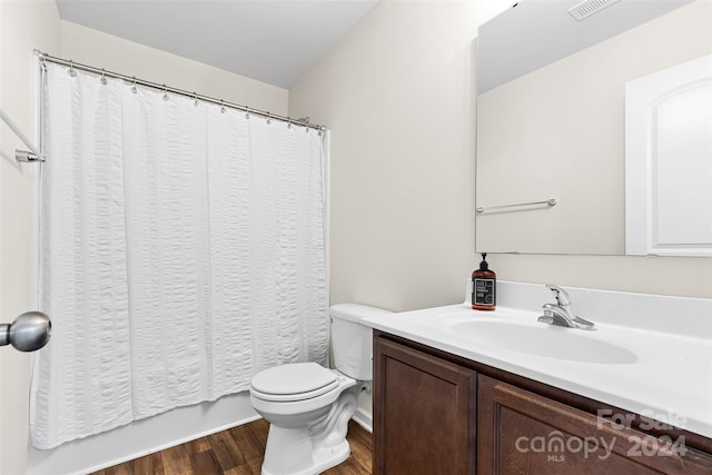 full bathroom with hardwood / wood-style flooring, vanity, shower / bath combination with curtain, and toilet