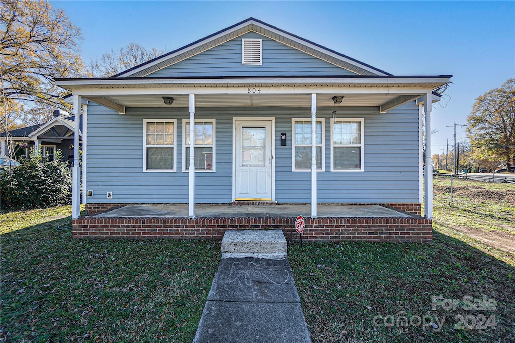 bungalow with covered porch and a front lawn