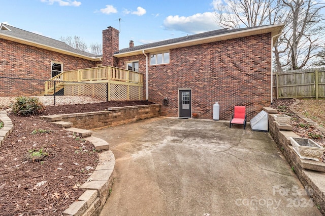 rear view of property with a wooden deck and a patio