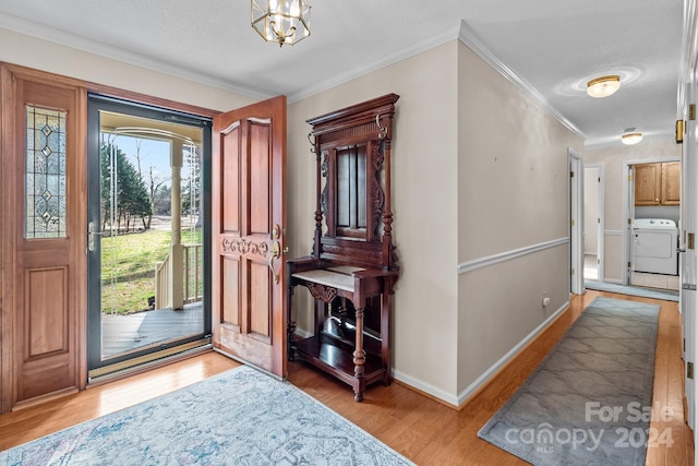 entryway with a notable chandelier, washer / clothes dryer, light wood-type flooring, a textured ceiling, and ornamental molding