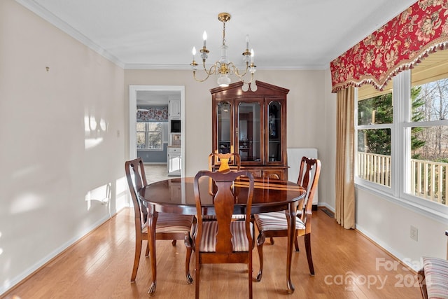 dining room with an inviting chandelier, light wood-type flooring, and ornamental molding