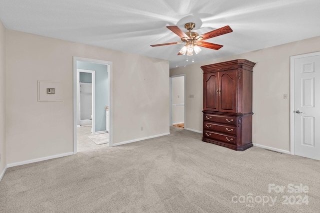 unfurnished bedroom featuring ceiling fan, a spacious closet, and light carpet