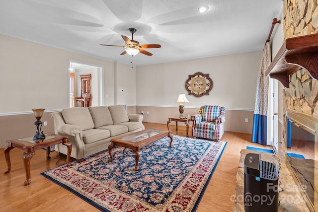 living room featuring ceiling fan, a fireplace, and light wood-type flooring