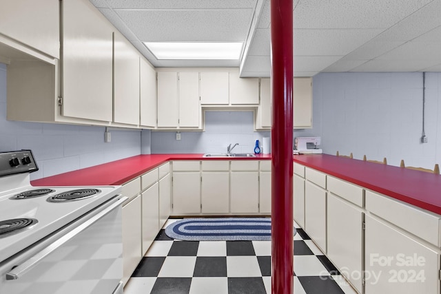 kitchen with white range with electric stovetop, white cabinetry, and sink