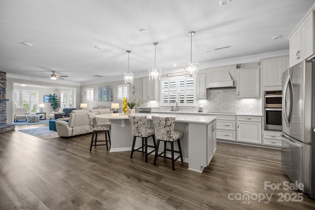 kitchen with a kitchen island, white cabinetry, stainless steel appliances, a kitchen breakfast bar, and hanging light fixtures