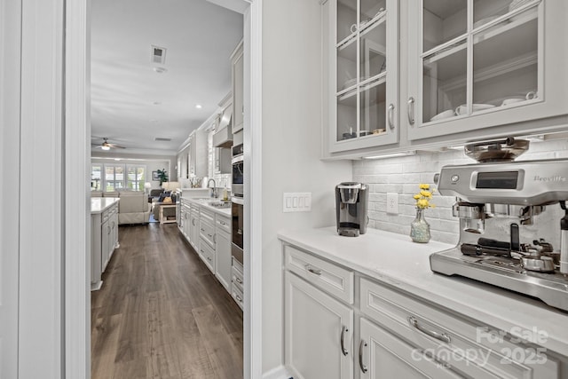 bar with tasteful backsplash, white cabinets, ceiling fan, and dark hardwood / wood-style flooring