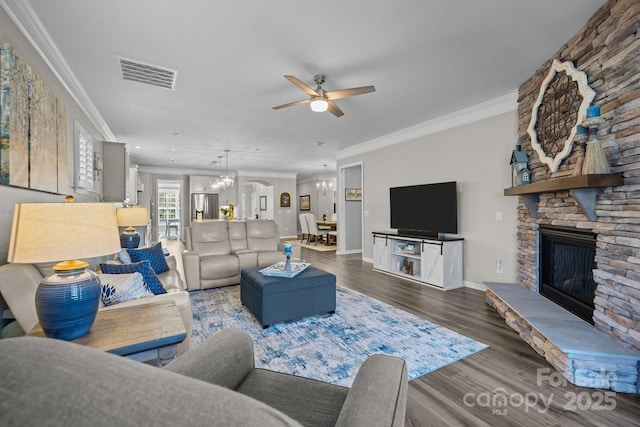 living room with ceiling fan with notable chandelier, hardwood / wood-style flooring, ornamental molding, and a fireplace