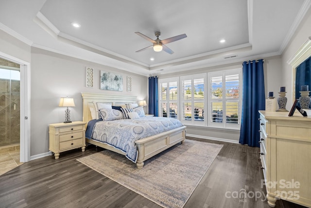 bedroom with ensuite bath, dark hardwood / wood-style floors, a raised ceiling, ceiling fan, and crown molding