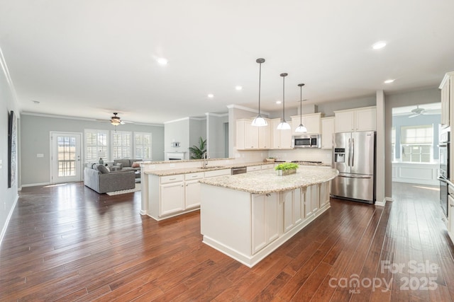 kitchen with kitchen peninsula, appliances with stainless steel finishes, sink, decorative light fixtures, and a center island