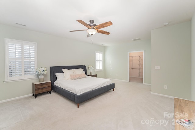 bedroom with ceiling fan, light carpet, a closet, and a spacious closet