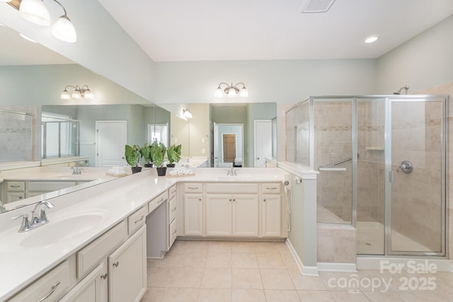 bathroom with a shower with door, vanity, and tile patterned flooring