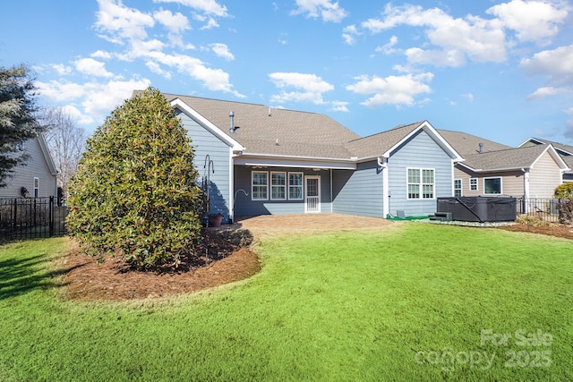 rear view of house featuring a hot tub and a lawn