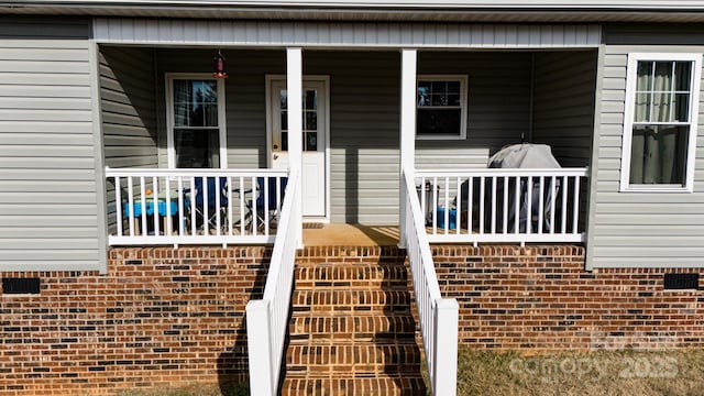 view of exterior entry featuring covered porch