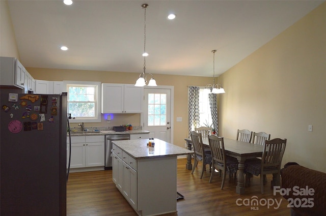 kitchen with hanging light fixtures, stainless steel appliances, a center island, and white cabinets