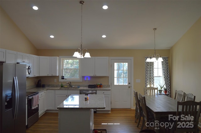 kitchen featuring stainless steel appliances, a center island, pendant lighting, and a notable chandelier