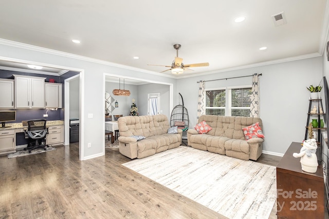 living room with hardwood / wood-style floors, built in desk, ceiling fan, and crown molding