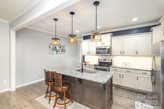 kitchen featuring light stone countertops, stainless steel appliances, a kitchen island with sink, sink, and pendant lighting